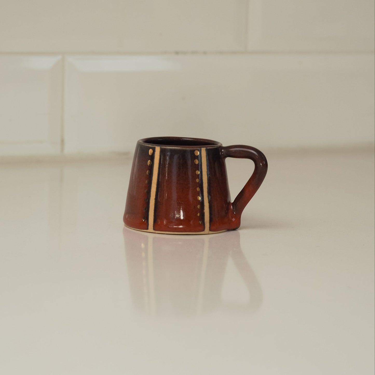 Dark red ceramic mug with decorative patterns on a white surface
