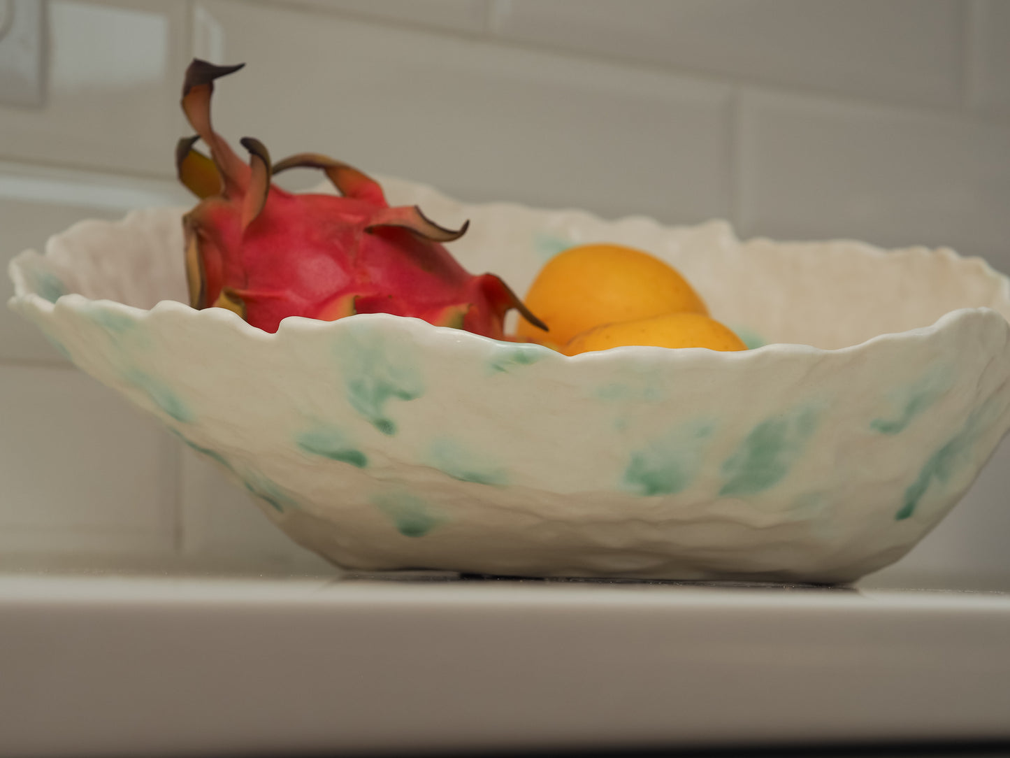 Decorative ceramic bowl with fruit on a white surface