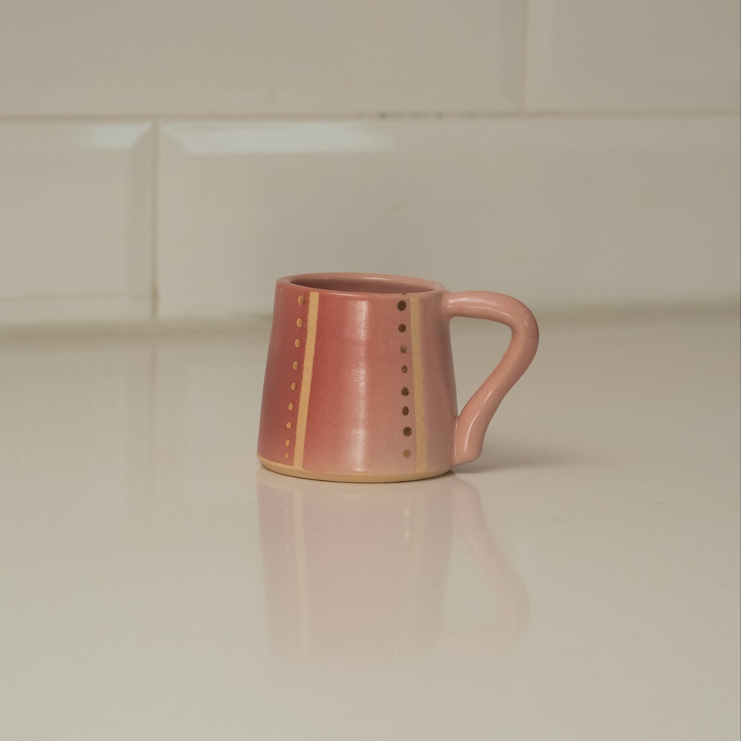 Pink ceramic mug on a light-colored surface with a neutral background