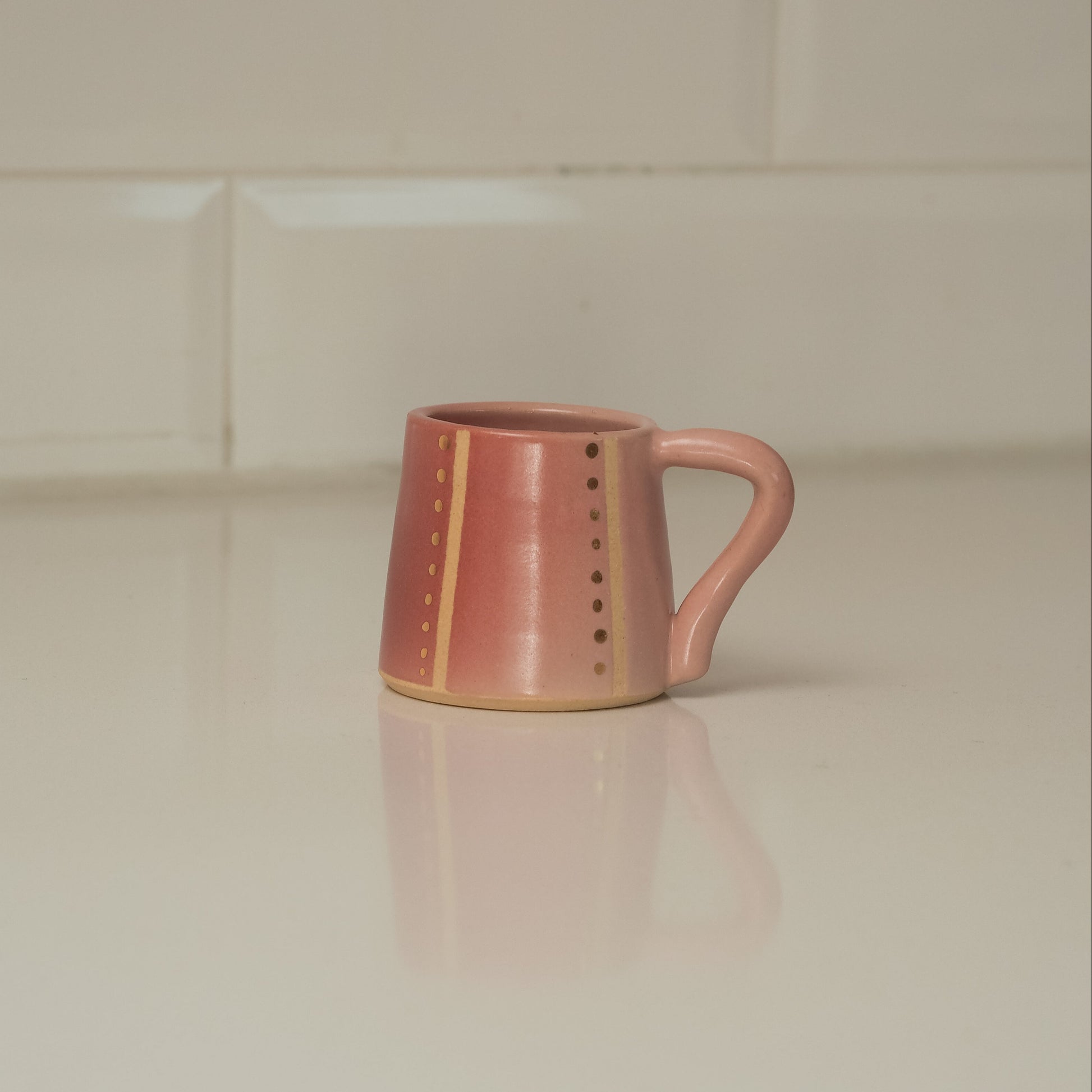 Pink ceramic mug on a light-colored surface with a neutral background