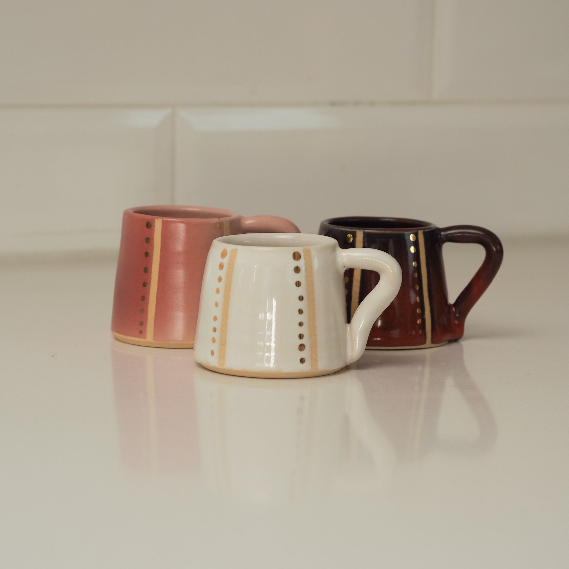 Three ceramic mugs with different designs on a white surface.