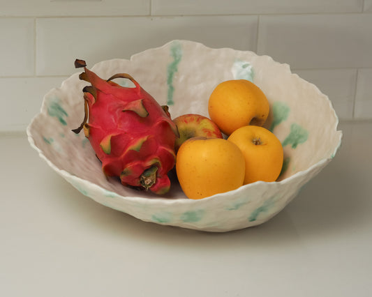 Fruit including a dragon fruit and oranges in a decorative bowl on a tiled wall background