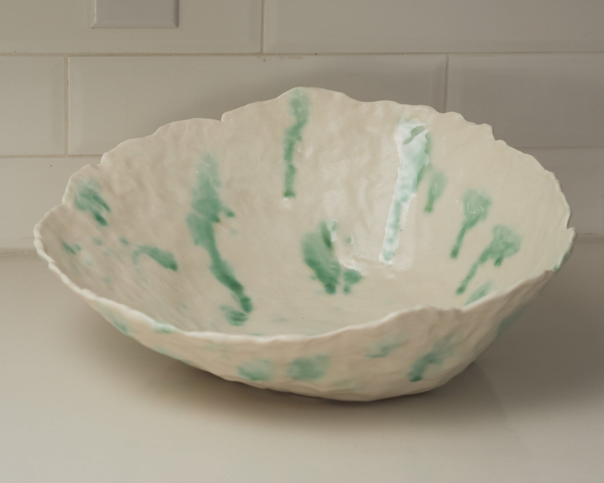 White ceramic bowl with green speckles on a neutral background