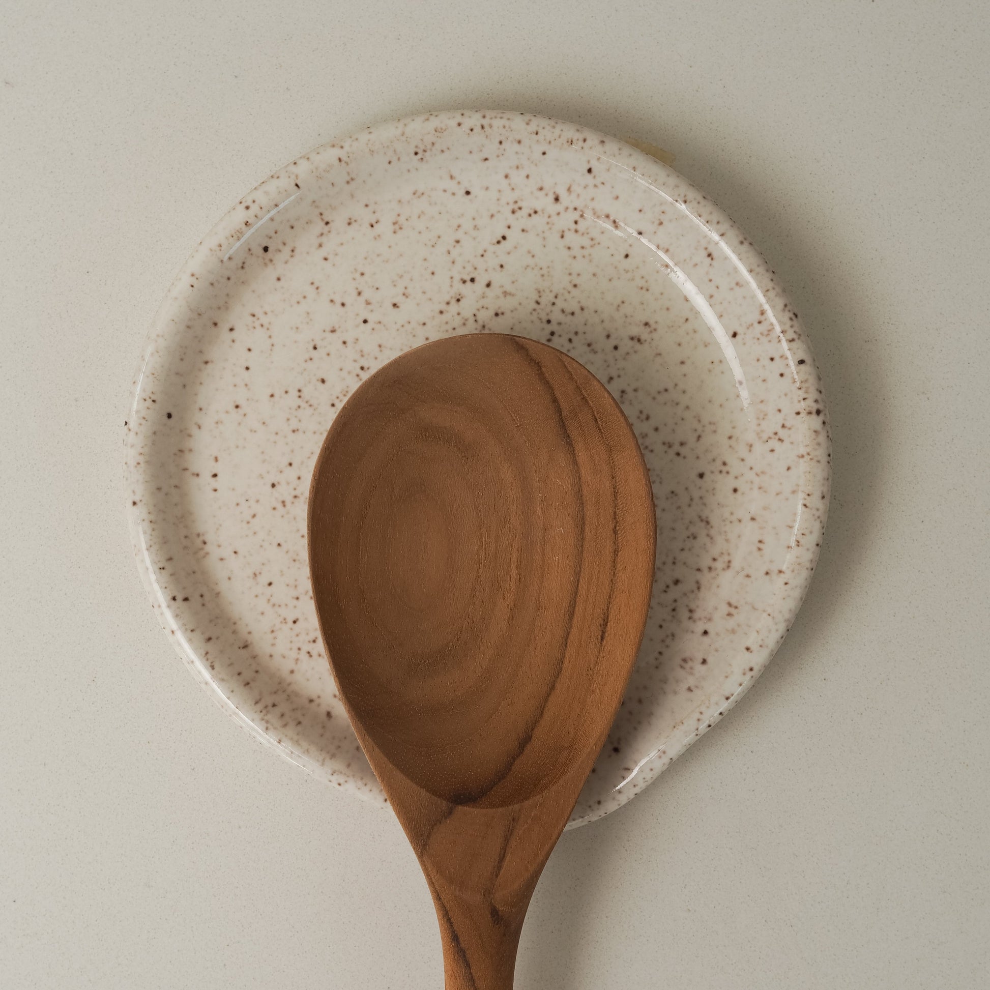 Wooden spoon on a speckled ceramic spoon rest